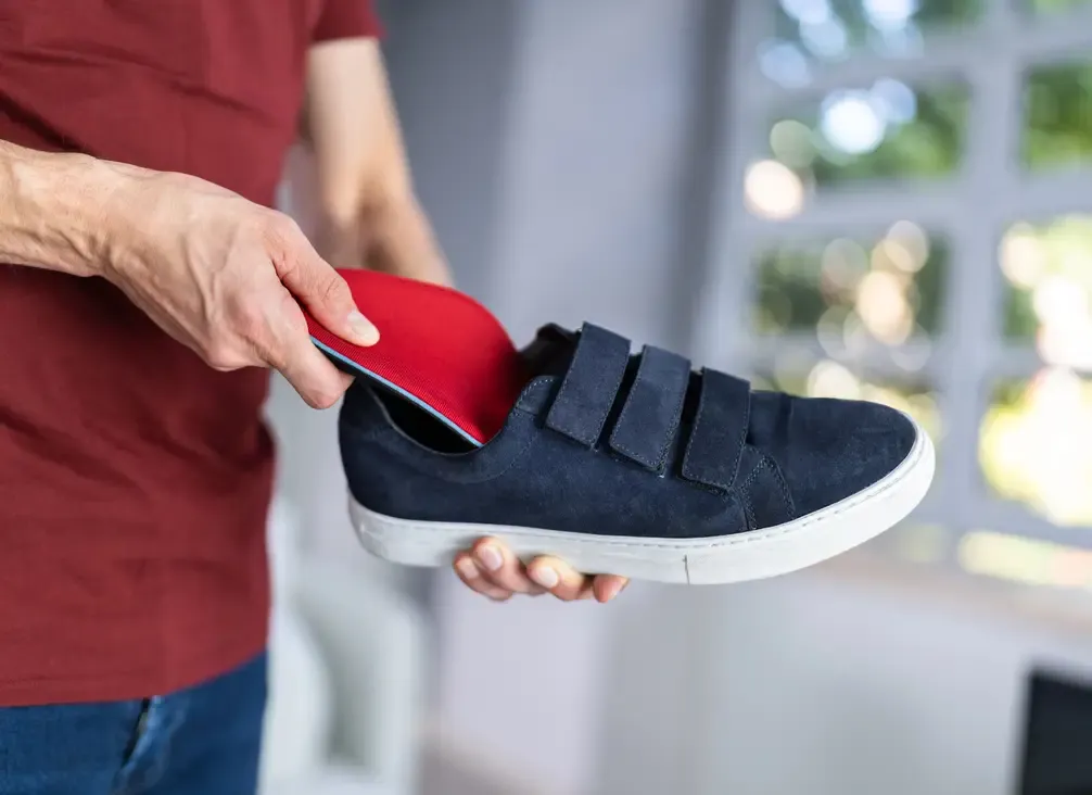 An orthotic insole being placed into a shoe