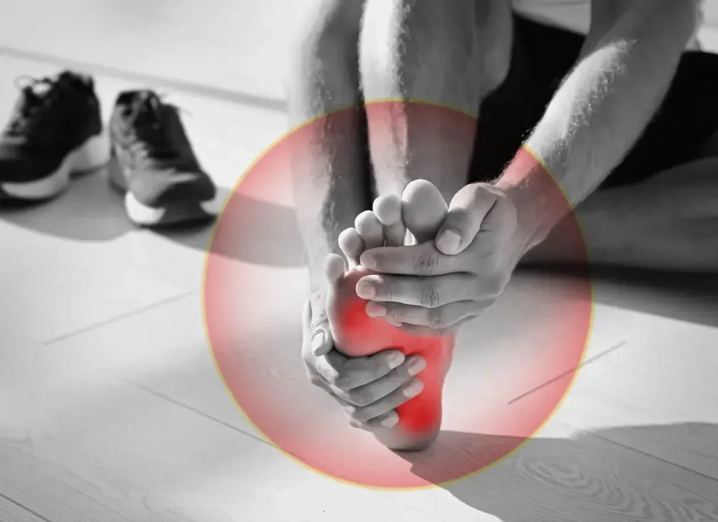 A person gripping the back of their heel, the painful area highlighted