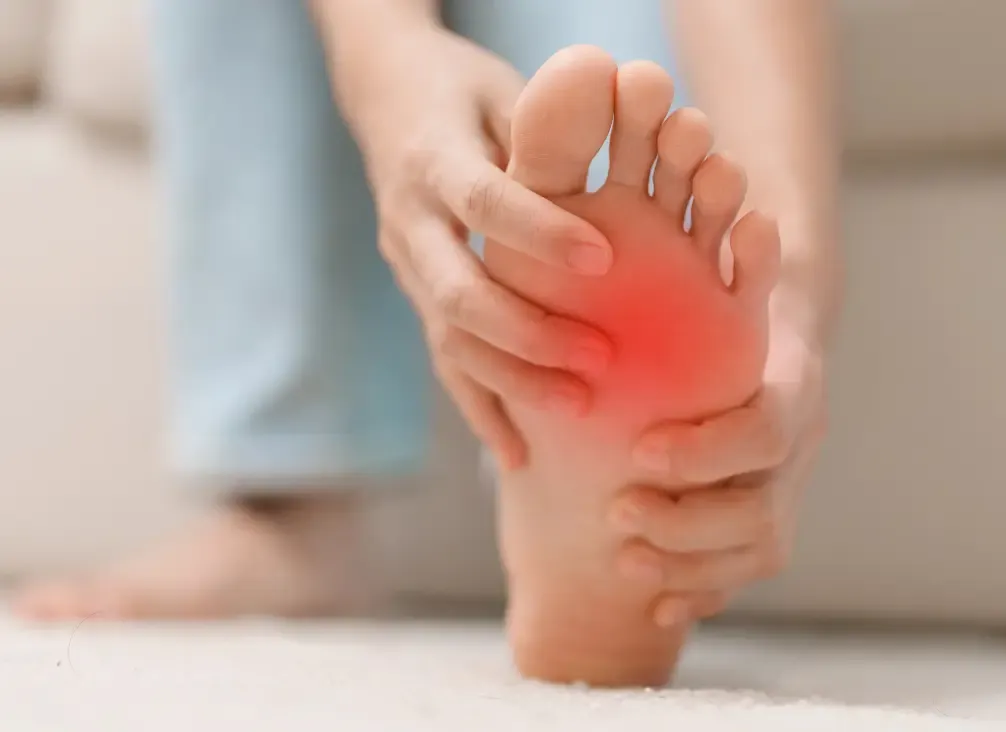 A person massaging the ball of their foot to relieve forefoot nerve pain