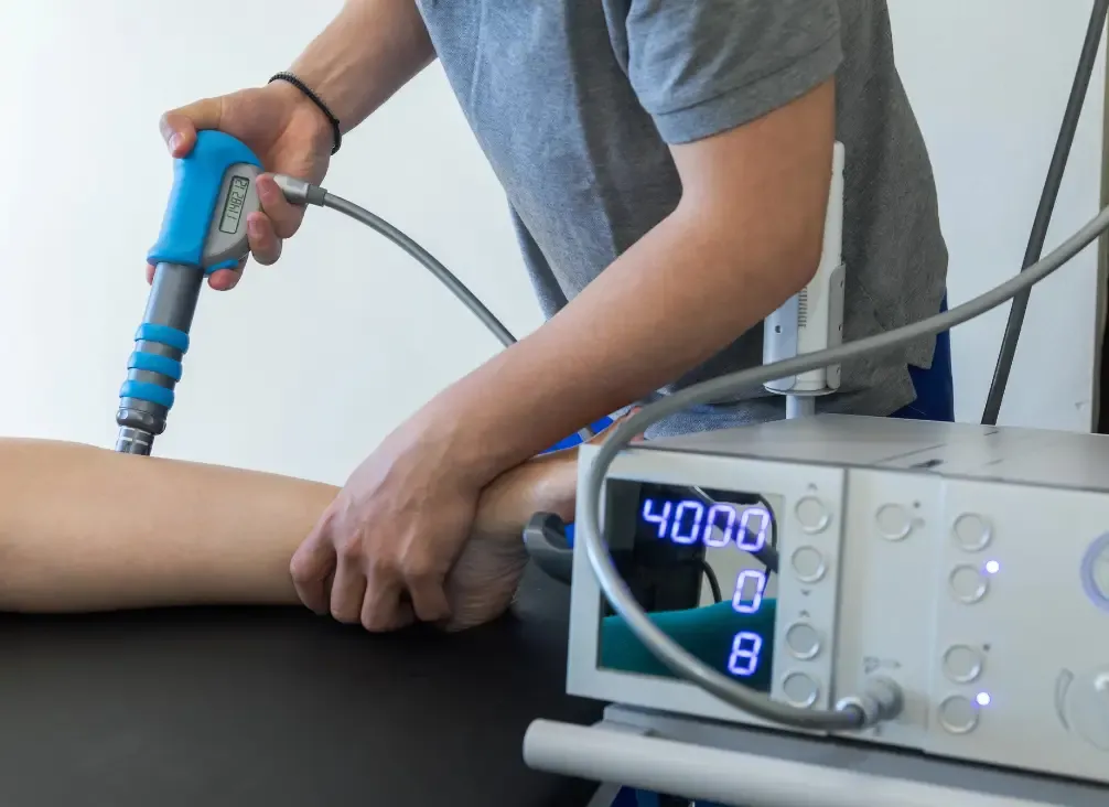 A podiatrist applying a shockwave therapy handpiece to a patient's heel