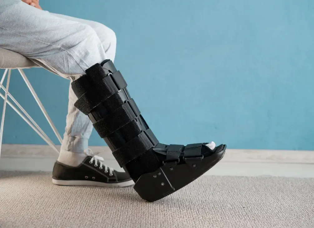 A CAM walker boot fitted to a patient's lower leg, showing the vertical side stays and strap positions