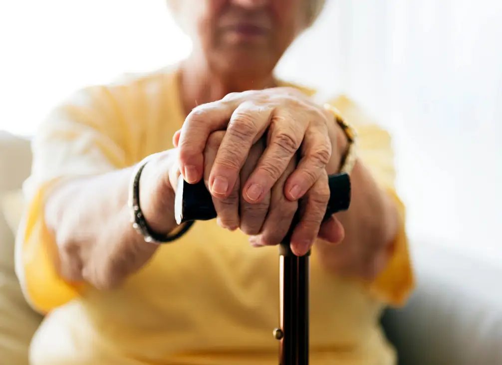 Elderly woman resting hands on walking cane – podiatry Brunswick support for aged foot care.