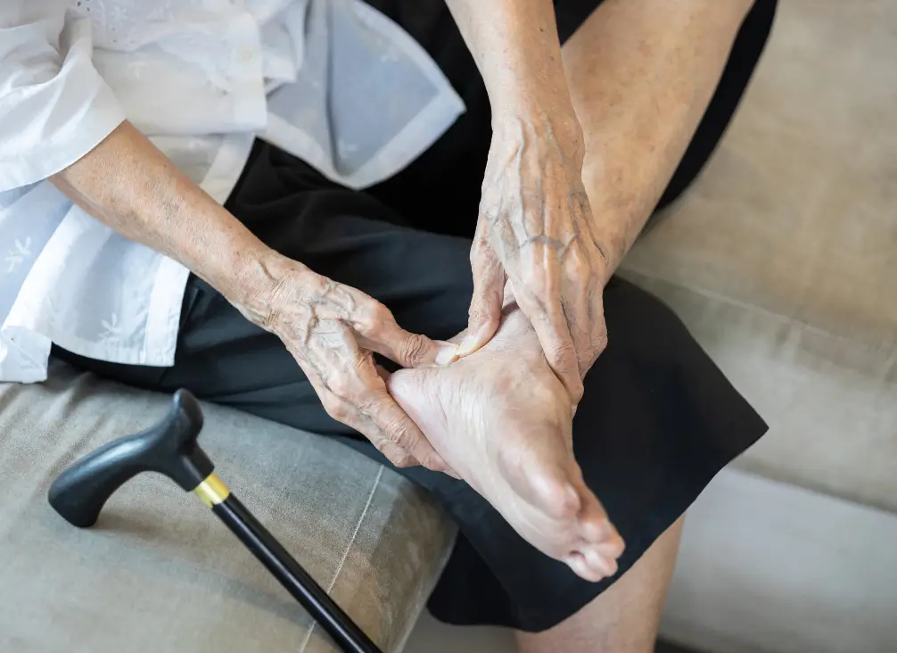 Elderly woman holding heel in discomfort – age-related foot care at podiatry Brunswick clinic.
