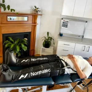 Patient using Normatec compression boots for leg recovery in Brunswick podiatry clinic