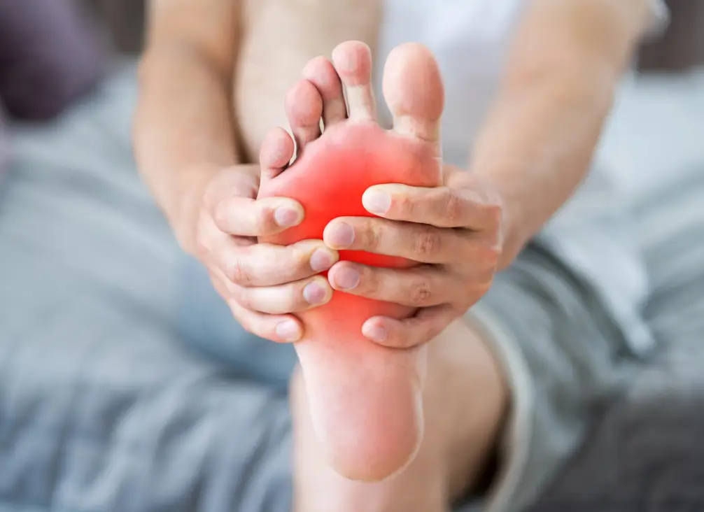 Man holding foot with red pain area indicating morning heel or arch pain.