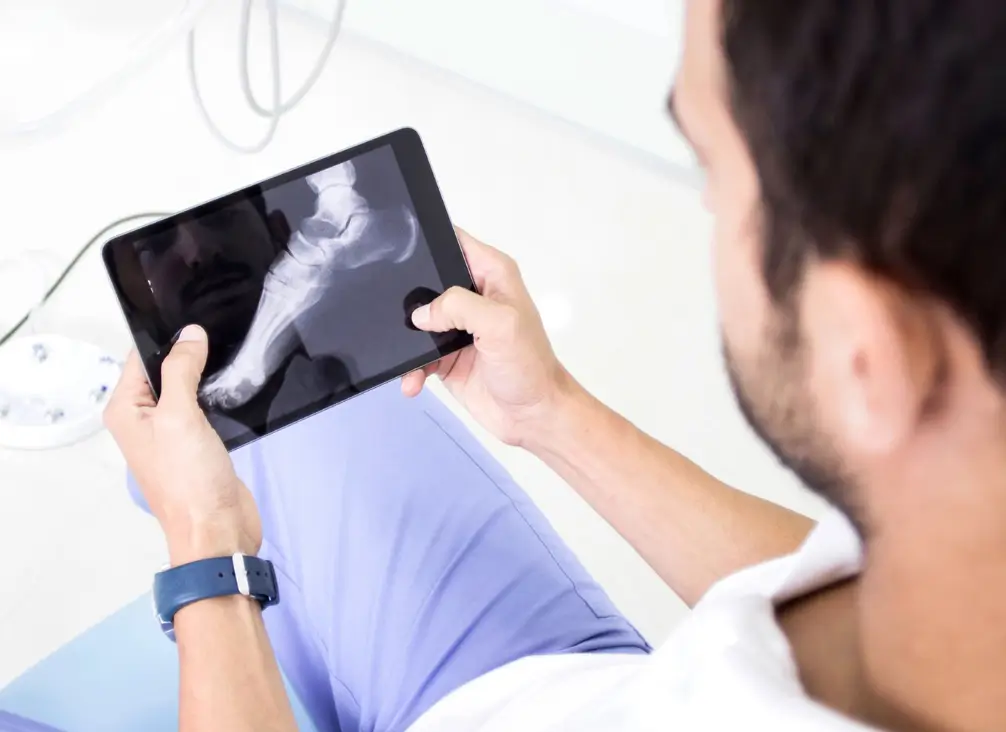 Podiatrist analysing foot X-ray on tablet during assessment