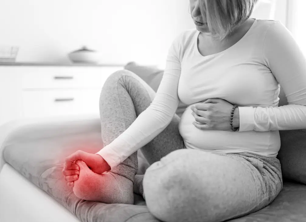 Pregnant woman holding painful swollen foot