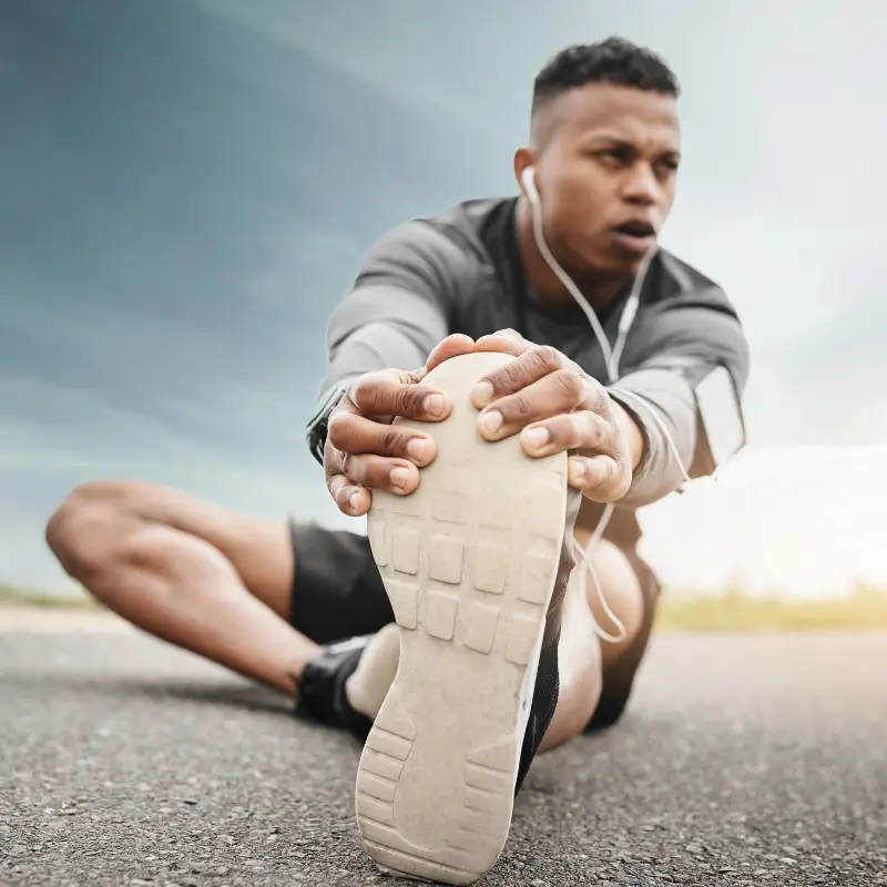 Male runner stretching leg before exercise – podiatrist foot pain treatment Brunswick