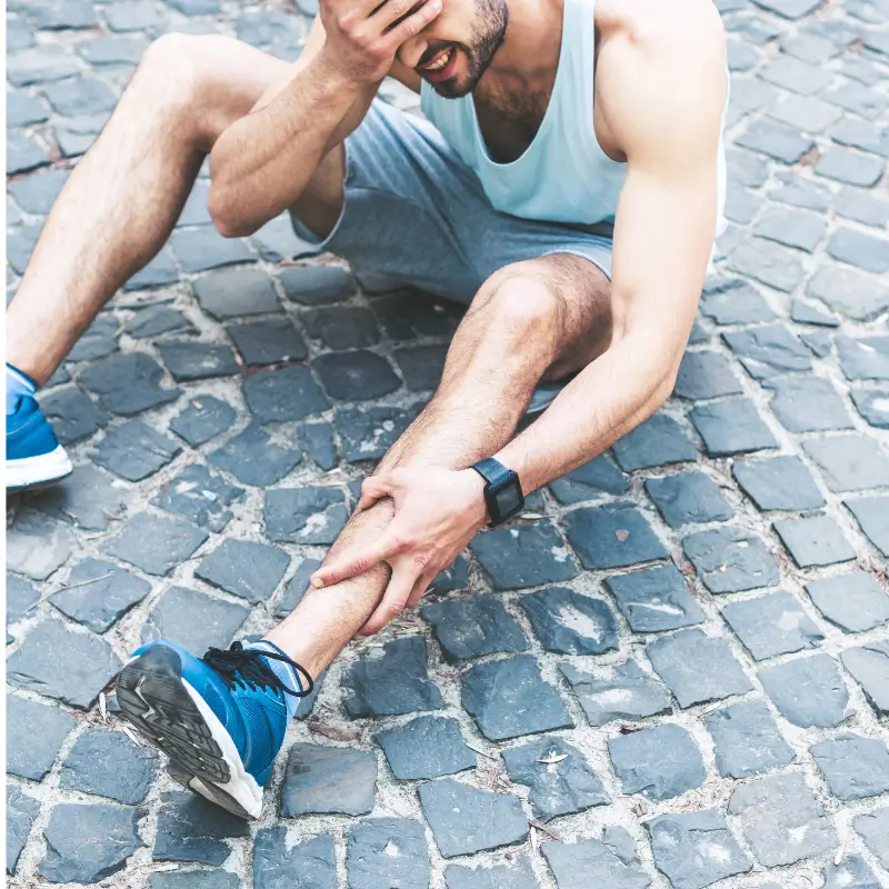 Runner clutching shin in pain on cobblestone street – shin splints podiatrist Brunswick