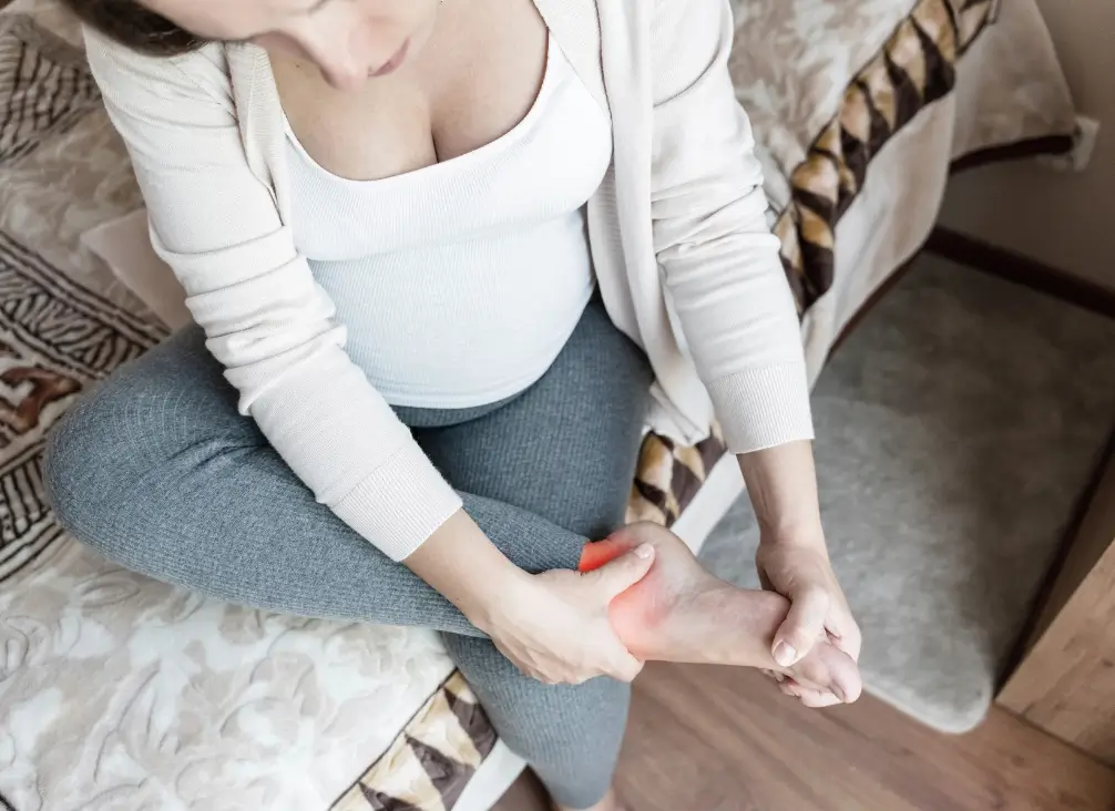 Pregnant woman holding sore heel – foot pain care by podiatry Brunswick during pregnancy.