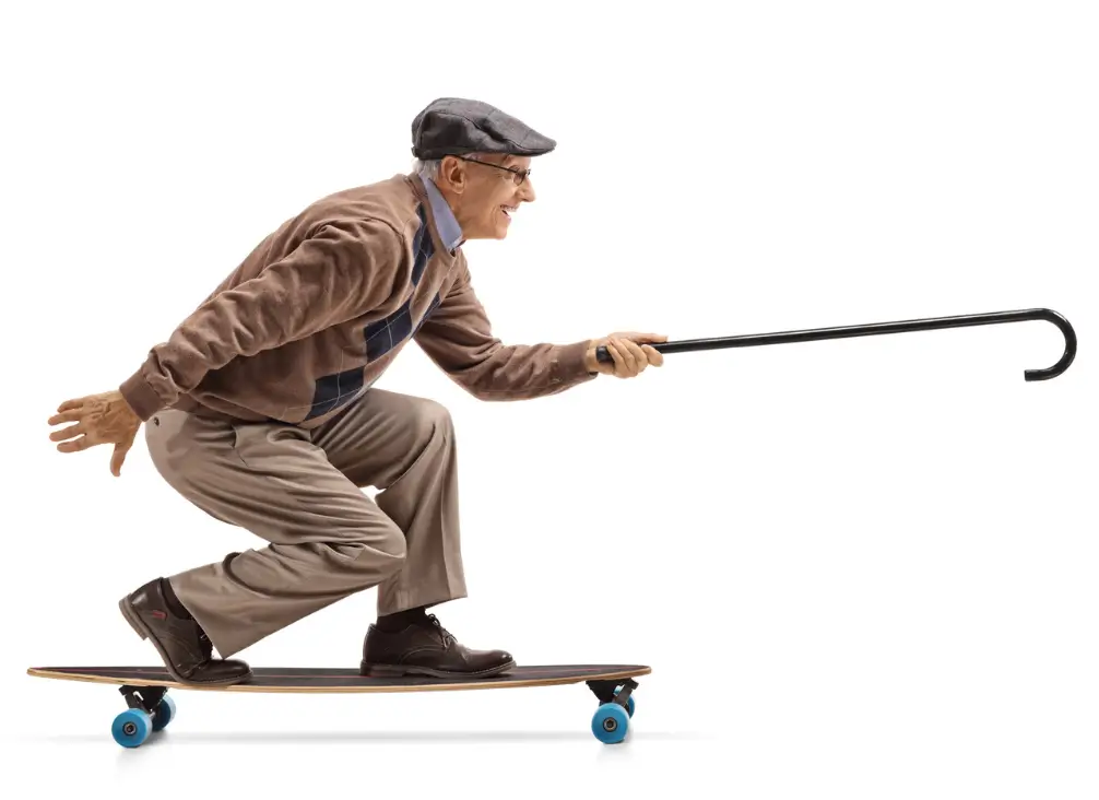 Energetic elderly man skateboarding with cane – healthy ageing supported by podiatry Brunswick care.