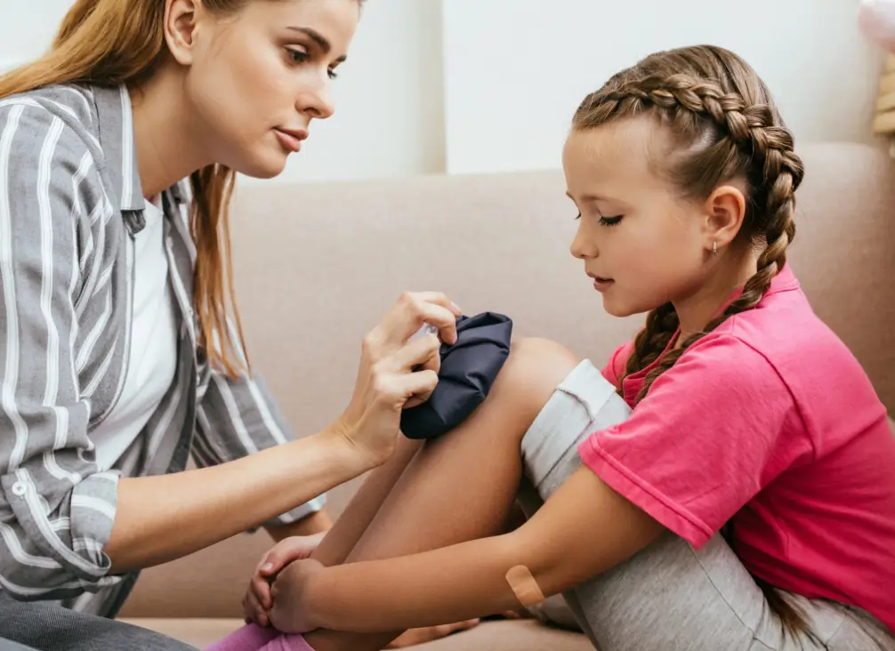 Mother applying ice pack to daughter’s sore knee from Osgood-Schlatter pain