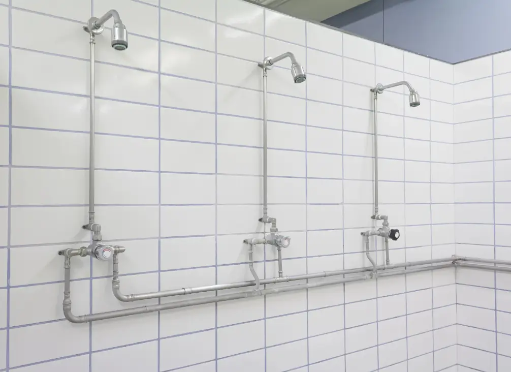 Communal shower facilities with tiled walls and exposed plumbing